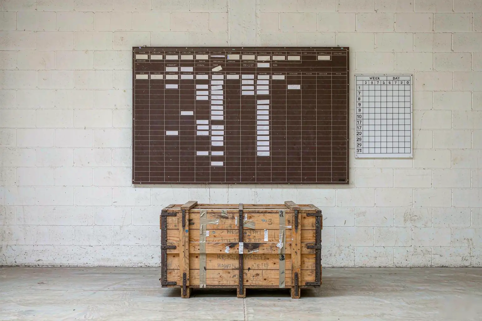 Casting payment terms milestone schedule on a foundry planning board beside a stencilled export crate