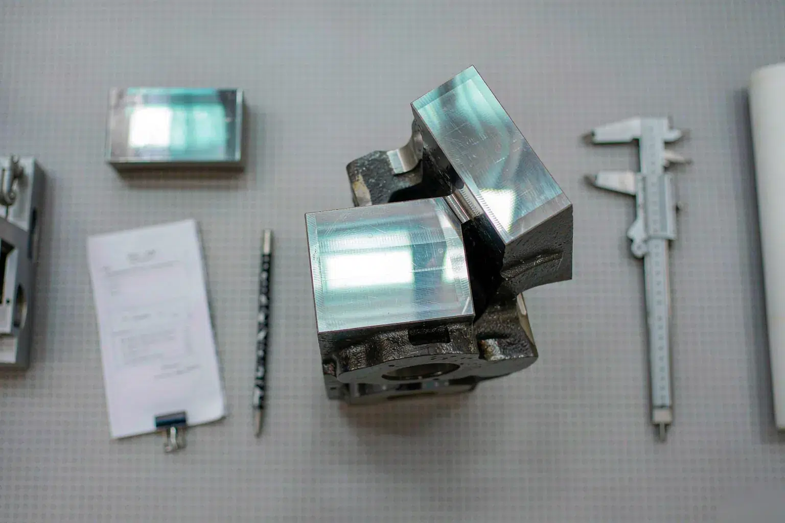 cast steel grades documentation with a machined steel casting bracket, an attached test coupon and a material test report on an inspection table