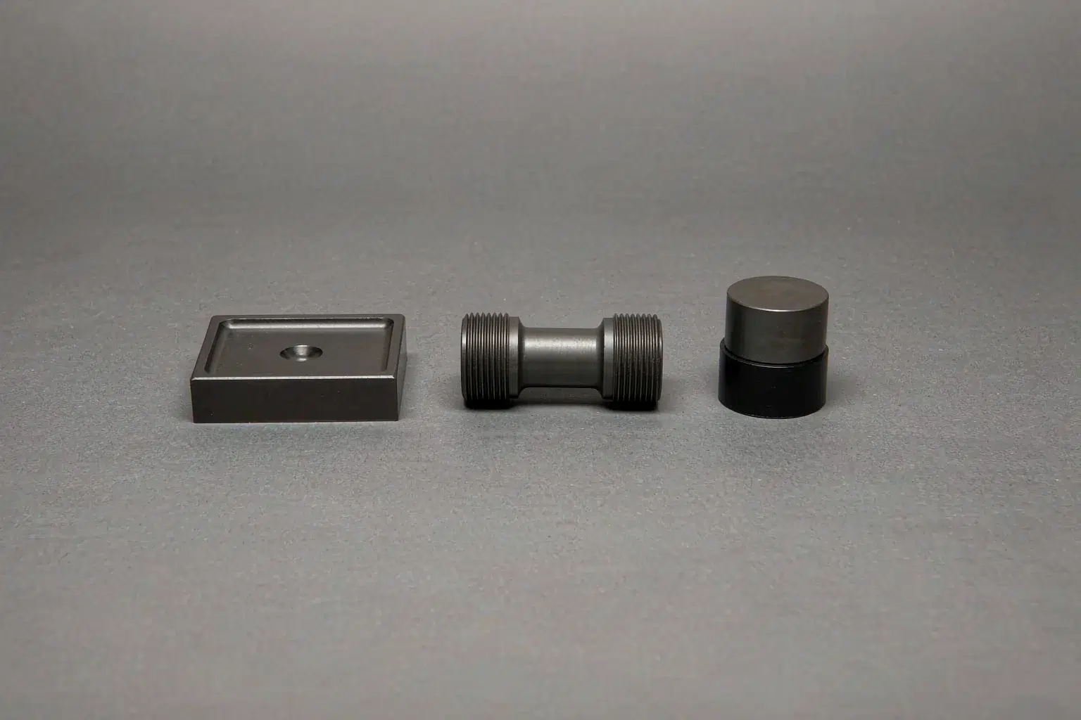 Casting supplier audit evidence: a hardness test block with an indentation, a machined tensile test specimen and a polished mounted section sample on a laboratory bench
