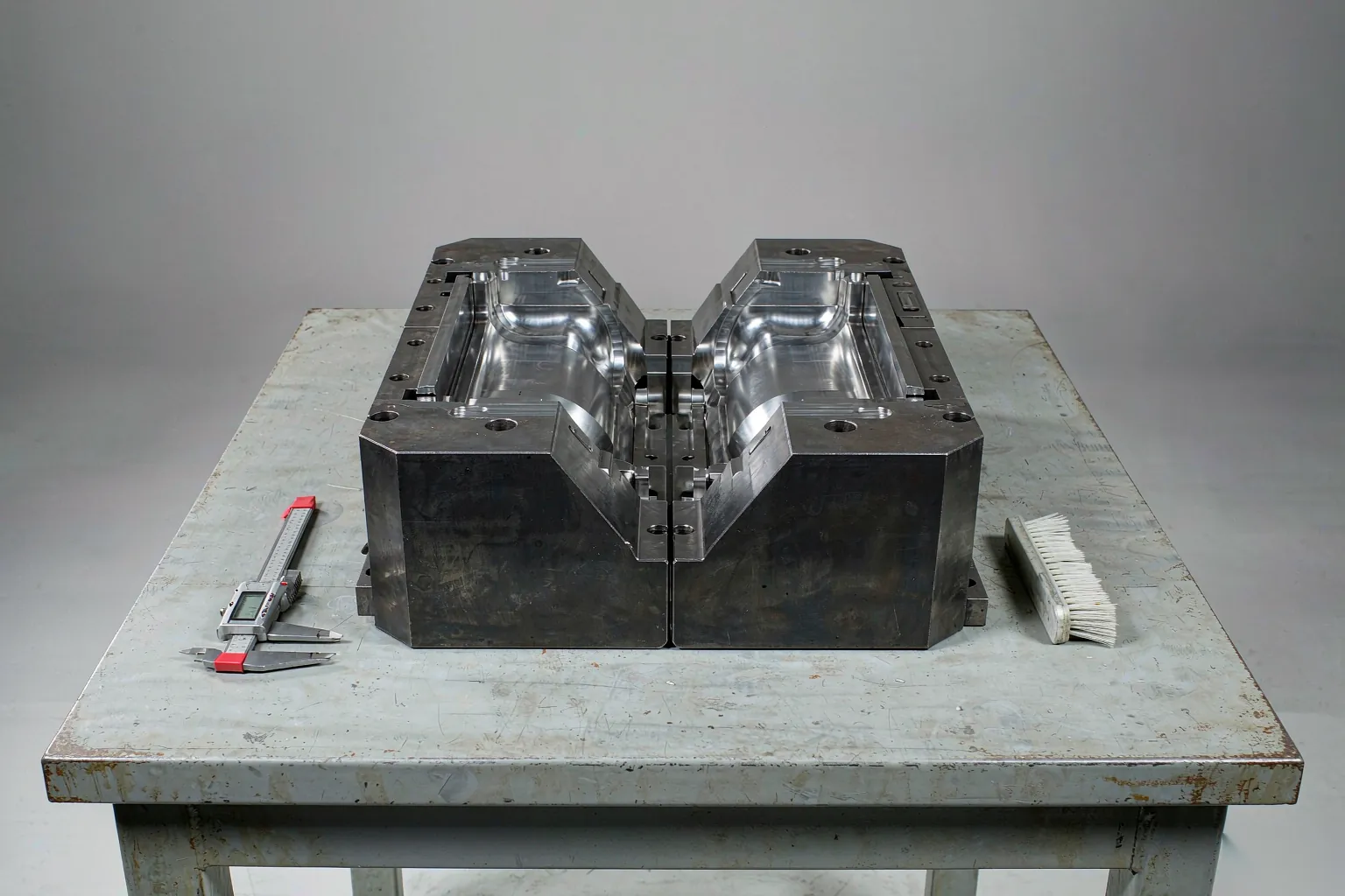 casting tooling maintenance: die casting die halves opened on a toolroom bench with calipers and a cleaning brush