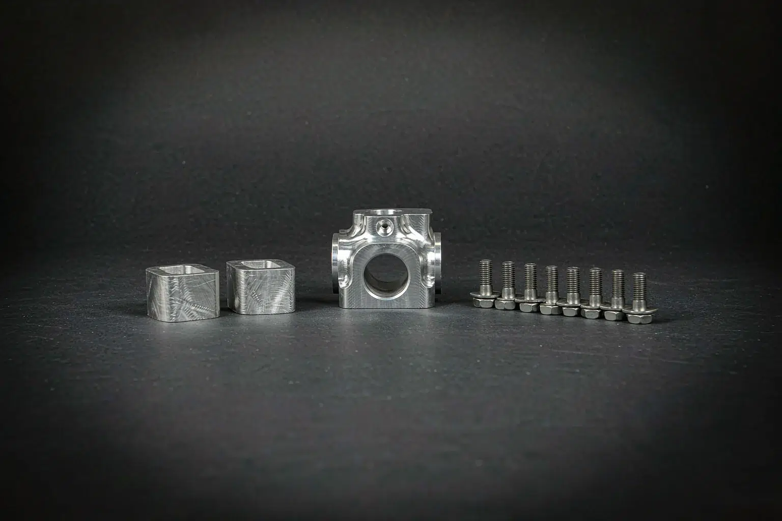 Casting part consolidation: small aluminium investment casting beside two machined billet parts and eight fasteners